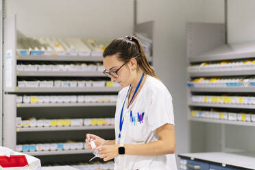 Female worker packing medicines while standing in pharmacy - DGOF01300