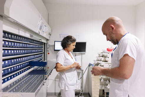 Männliche und weibliche Apotheker bei der Arbeit im Lagerraum eines Krankenhauses - DGOF01305