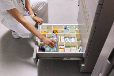 Female doctor searching medicines in drawer at pharmacy - DGOF01313
