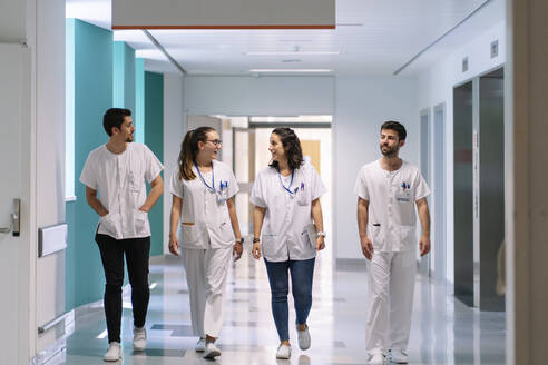 Doctors discussing while walking in corridor at hospital - DGOF01323