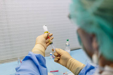 Close-up of female pharmacist holding vial and syringe in laboratory - DGOF01367