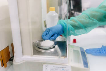 Hands of female scientist measuring powder medicine on scale in laboratory - DGOF01385