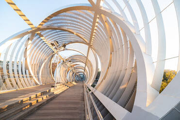Perspektivische Innenansicht der schraubenförmigen, kegelförmigen Arganzuela-Brücke mit ineinander verschlungenen Metallspiralen, die sich bei Sonnenuntergang in Madrid diagonal kreuzen - ADSF15043