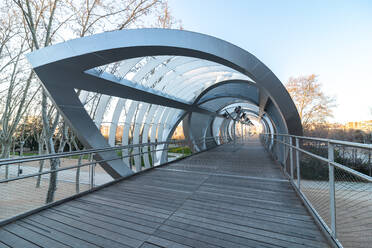 Perspektivische Innenansicht der schraubenförmigen, kegelförmigen Arganzuela-Brücke mit ineinander verschlungenen Metallspiralen, die sich bei Sonnenuntergang in Madrid diagonal kreuzen - ADSF15044