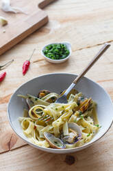 Hoher Winkel der Schüssel mit frisch gekochten Spaghetti mit Muscheln auf Holztisch in Café platziert - ADSF15148