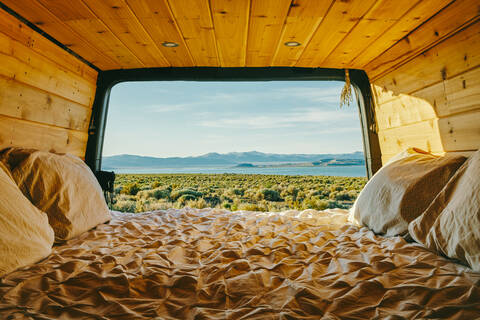 View of mono lake from open doors of camper van with bed in California stock photo