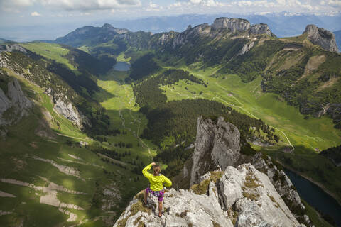 Rock climber on summit over valley, Alpstein, Appenzell, Switzerland stock photo