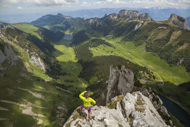 Rock climber on summit over valley, Alpstein, Appenzell, Switzerland - CAVF88754