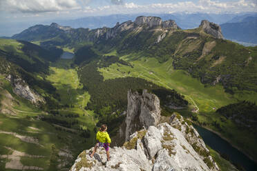 Rock climber on summit over valley, Alpstein, Appenzell, Switzerland - CAVF88755