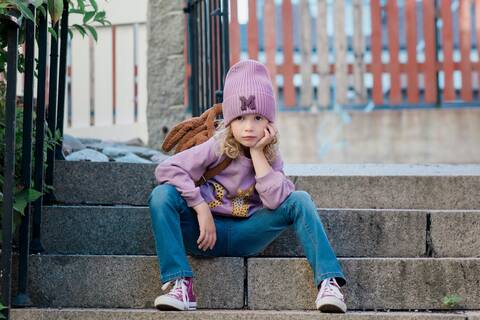 Porträt eines jungen Mädchens auf einer Stufe sitzend mit abwartender Haltung, lizenzfreies Stockfoto