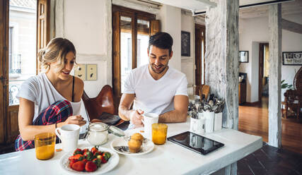 Young couple sitting at table and having breakfast at home - EHF00894