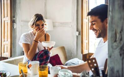 Happy young couple sitting at table and having breakfast at home - EHF00903