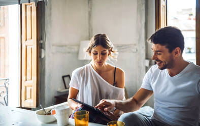 Young couple watching tablet while having breakfast at home - EHF00907