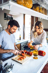 Junger Mann bereitet mit Freundin in der Küche zu Hause Essen zu - EHF00929