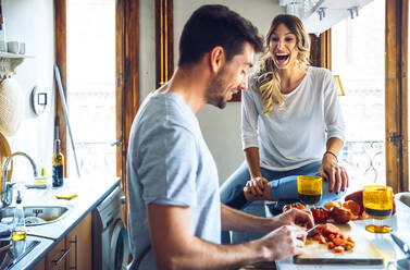 Young man preparing food with laughing girlfriend in kitchen at home - EHF00930