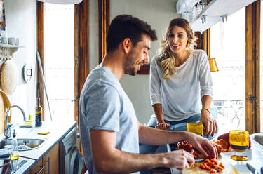 Junger Mann bereitet Essen zu und spricht mit seiner Freundin in der Küche zu Hause - EHF00932