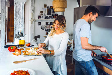 Glückliches junges Paar bei der gemeinsamen Zubereitung von Speisen in der Küche zu Hause - EHF00937
