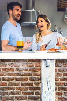 Lachendes junges Paar bei der Zubereitung von Speisen in der Küche zu Hause - EHF00945