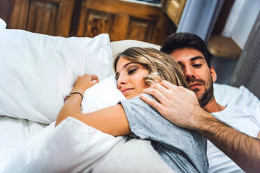Affectionate young couple lying in bed at home - EHF00984