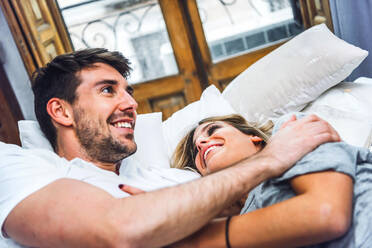 Happy affectionate young couple lying in bed at home - EHF00986