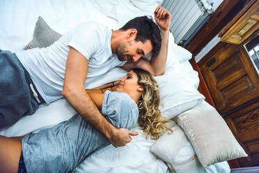 Affectionate young couple cuddling in bed at home - EHF00990