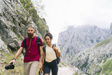 Wanderer mit Kamera in der Hand beim Wandern auf einem Bergpfad an der Ruta Del Cares, Asturien, Spanien - DGOF01390