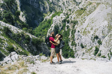Junger Mann, der eine Frau umarmt, während er auf einem Berg an der Ruta Del Cares steht, Asturien, Spanien - DGOF01396