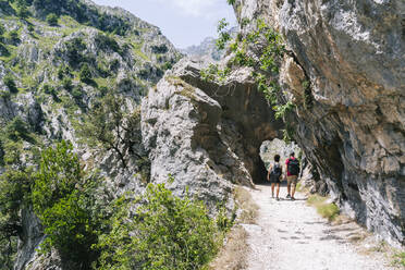 Hikers walking on mountain path at Ruta Del Cares, Asturias, Spain - DGOF01398