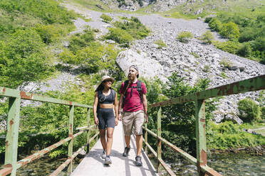 Young hikers walking on bridge at Ruta Del Cares, Asturias, Spain - DGOF01404