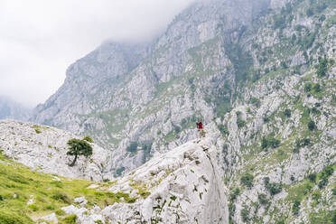 Junger Mann bewundert die Aussicht, während er auf einem Berg an der Ruta Del Cares steht, Asturien, Spanien - DGOF01411