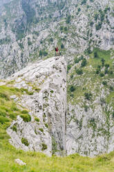 Mann betrachtet die Aussicht, während er auf einem Berggipfel an der Ruta Del Cares steht, Asturien, Spanien - DGOF01412