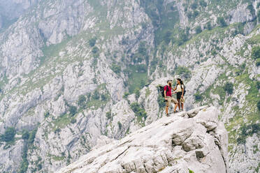 Couple standing on mountain peak at Ruta Del Cares, Asturias, Spain - DGOF01415