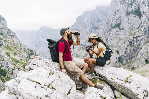 Ehepaar ruht sich auf einem Bergfelsen an der Ruta Del Cares, Asturien, Spanien, aus - DGOF01417