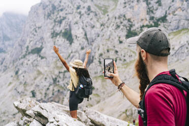 Mann fotografiert eine Frau auf einem Berggipfel an der Ruta Del Cares, Asturien, Spanien - DGOF01423