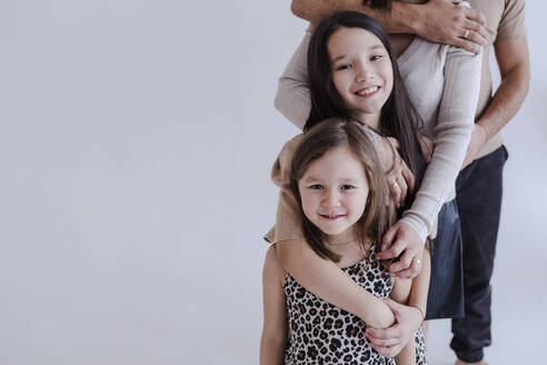 Familie umarmt sich gegenseitig von hinten, während sie im Studio steht - OGF00523