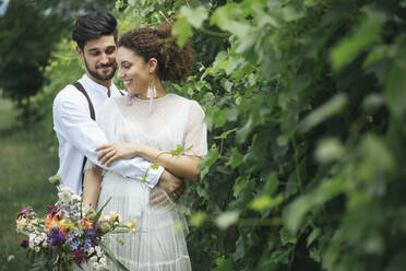 Bräutigam umarmt Braut, während er im Garten steht - ALBF01481