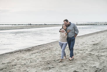Romantisches reifes Paar umarmt beim Spaziergang am Strand gegen den Himmel - UUF21201