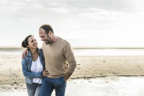 Fröhliches reifes Paar, das sich umarmt, während es am Wochenende am Meer steht - UUF21216