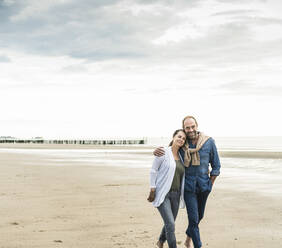 Verliebtes Paar spaziert am Strand gegen den Himmel bei Sonnenuntergang - UUF21232