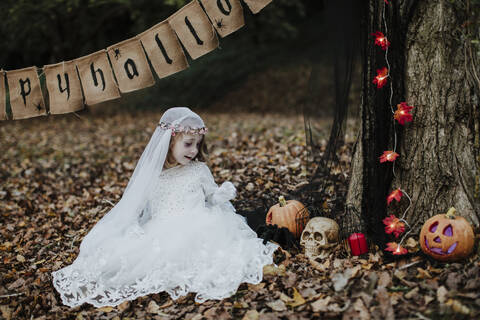 Cute little girl looking at halloween decoration in forest stock photo