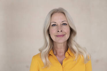 Close-up of confident businesswoman with blond hair against wall in office - MOEF03204