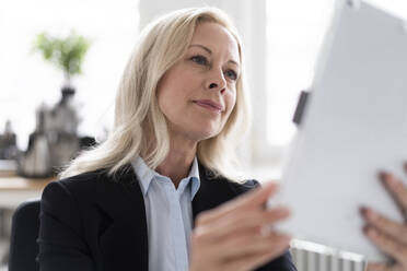 Nahaufnahme einer selbstbewussten Unternehmerin, die ein digitales Tablet im Home Office benutzt - MOEF03229