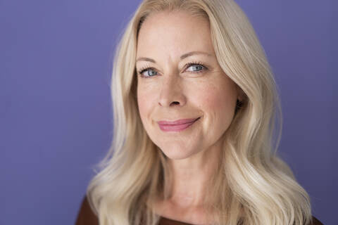 Close-up of smiling female professional against purple wall in office stock photo