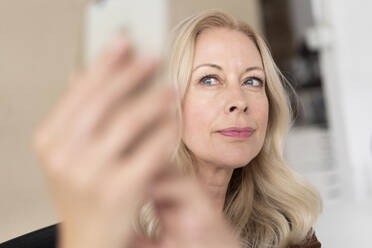 Close-up of beautiful businesswoman taking selfie with smart phone in office - MOEF03274