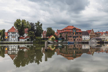 Deutschland, Schleswig-Holstein, Gluckstadt, Häuser am Wasser, die sich auf der glänzenden Oberfläche der Elbe spiegeln - KEBF01633