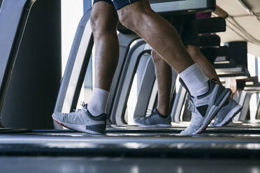 Beine von Sportlern, die auf Laufbändern im Fitnessstudio laufen - ABZF03285