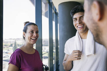 Lächelnde multiethnische Sportler unterhalten sich in der Pause im Fitnessstudio - ABZF03301