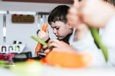 Kleine Mädchen und Jungen schneiden und schälen reifes Gemüse beim Kochen gesunden Salat in der Küche zusammen - ADSF15222