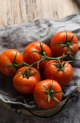 From above of wet clean tomatoes placed on gray fabric napkin on grey concrete table background - ADSF15226