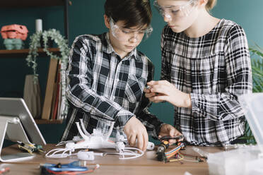 Geschwister bauen Quadcopter auf dem Tisch, während sie zu Hause stehen - ALBF01521